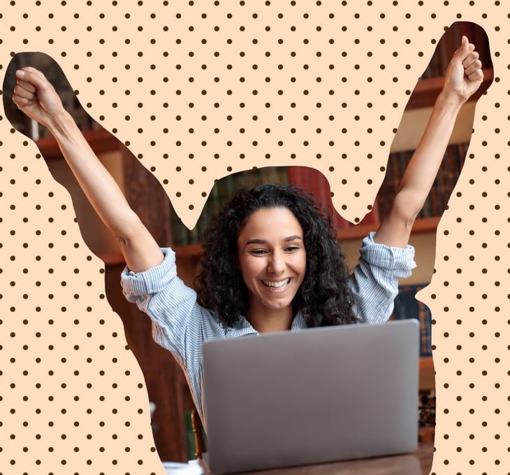 Woman infront of a laptop, raising her hands, looking happy 